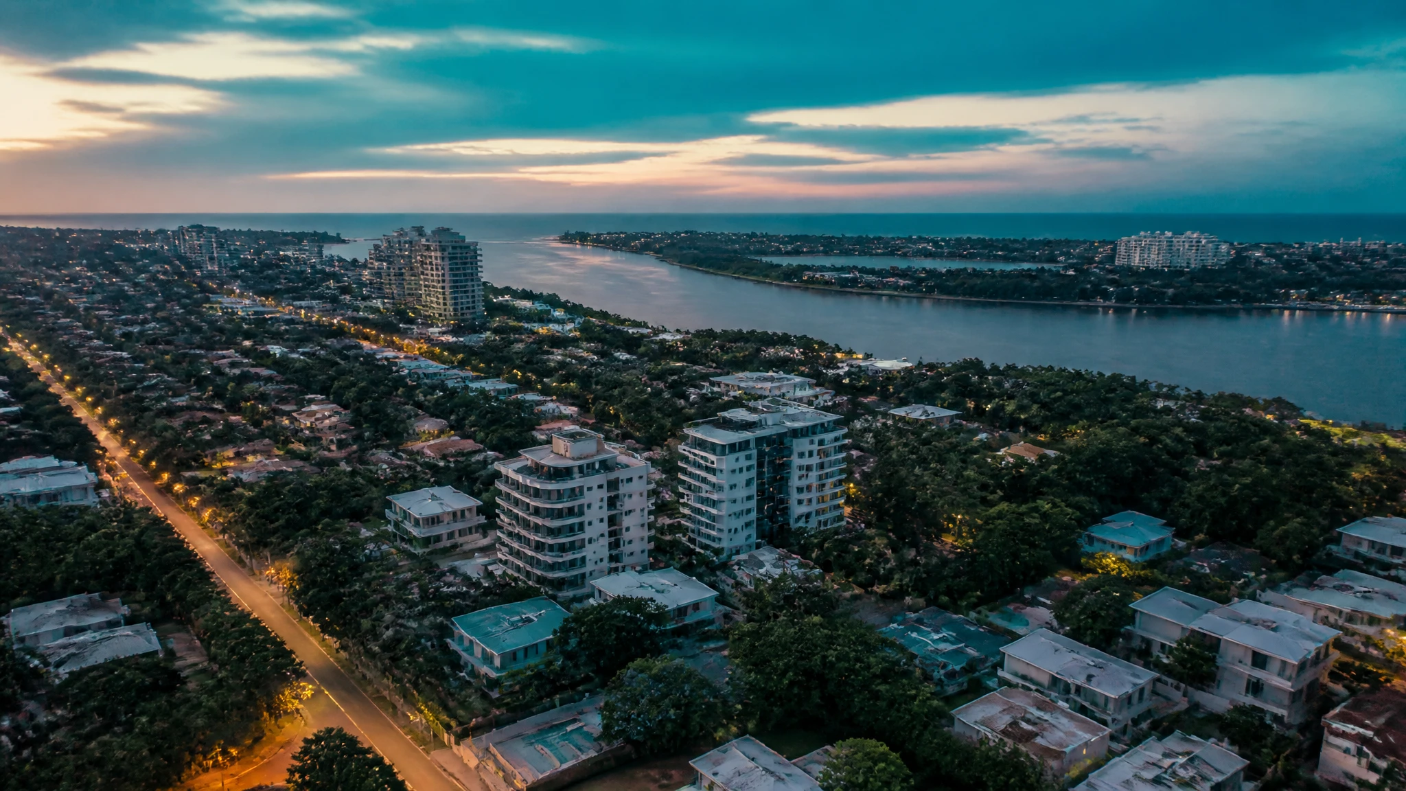 Vista aérea del sector de Miramar al atardecer, con arborización densa, avenidas y el río al fondo.